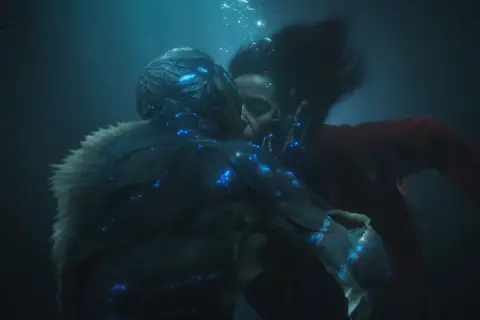 La forma dell'acqua recensione: un bacio subacqueo tra una donna e una creatura anfibia, illuminati da luci blu bioluminescenti.