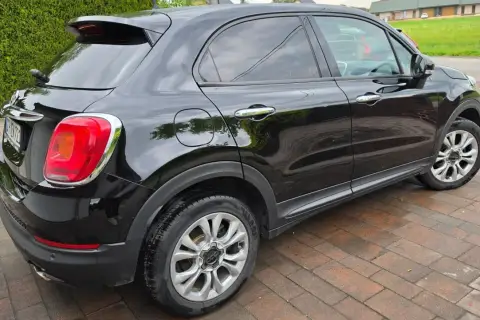 Czarny Fiat 500X widziany z boku, na brukowanym podjeździe.