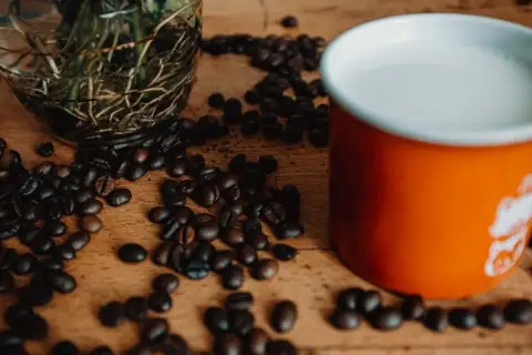 Ziarna kawy i kubek z mlekiem. Zastanawiasz się, jakie mleko do kawy będzie najlepsze?
