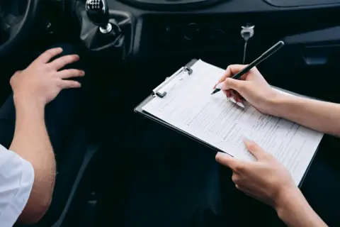 Kobieta wypełnia formularz ubezpieczeniowy w samochodzie, ustalając składkę ubezpieczeniową.