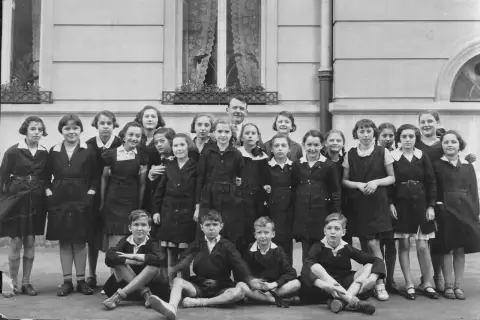 Uczniowie i nauczyciel przed budynkiem szkoły po francusku.