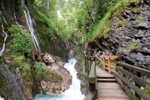 Holzstege führen durch die Klamm Berchtesgaden, vorbei an tosendem Wasser und moosbewachsenen Felsen.