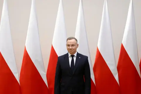 Prezydent Duda stoi przed polskimi flagami. Zastanawiamy się, dlaczego prezydent nie podpisał ustawy o mowie nienawiści przed marcem 2026.
