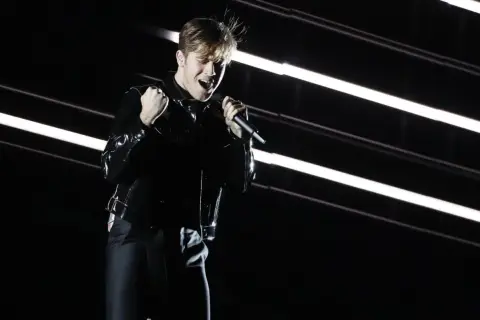 Benjamin Ingrosso levererar på scenen under Eurovision. Han sjunger passionerat med mikrofonen i handen, klädd i en glänsande svart jacka.