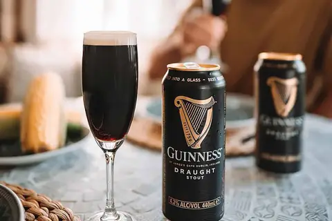 Une pinte de Guinness Draught Stout, avec son degré alcool de 4.2%, est servie à côté de canettes.