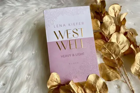 Lena Kiefer Roman "Westwell" auf flauschigem Untergrund, umrahmt von goldenen Blättern.