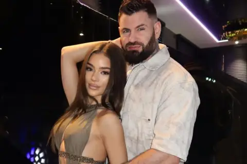 Wojtek Gola z dziewczyną, w eleganckich strojach, pozują do zdjęcia w stylowym wnętrzu.