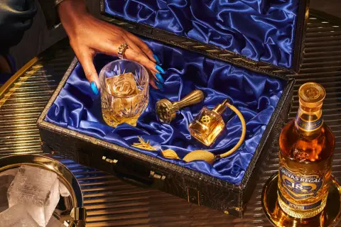 Skutki zbyt niskiej temperatury serwowania: dlaczego nie mrozić whisky. Elegancki zestaw z butelką Chivas Regal 18, szklanką z lodem i złotymi akcesoriami.
