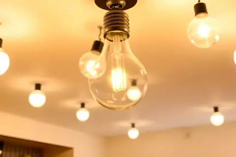 Un plafón con varias bombillas colgantes, algunas transparentes y otras opacas, iluminan cálidamente el techo.