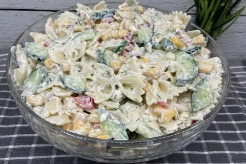 Pyszna, kremowa najlepsza sałatka z makaronem farfalle, ogórkiem, kukurydzą i ziołami.