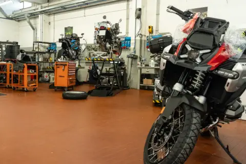 Officina moto con diverse moto in lavorazione. Un tecnico si chiede ogni quanto si fa il tagliando per mantenere al meglio il proprio mezzo.