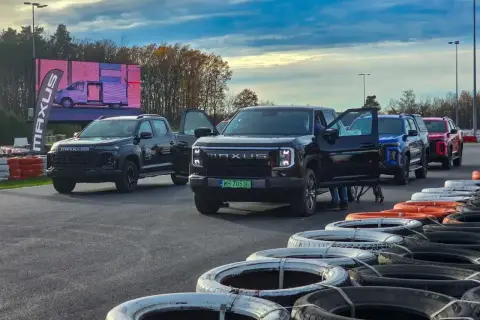 Kolekcja nowoczesnych pickupów Maxus, w tym czarny model z otwartymi drzwiami, ustawiona na torze wyścigowym.