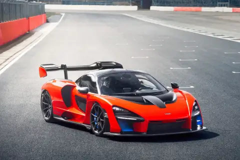Pomarańczowy McLaren Senna z czarnym spojlerem i detalami na torze wyścigowym.