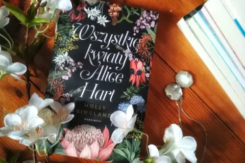 Wszystkie kwiaty Alice Hart otoczone białymi kwiatami, na drewnianym tle.