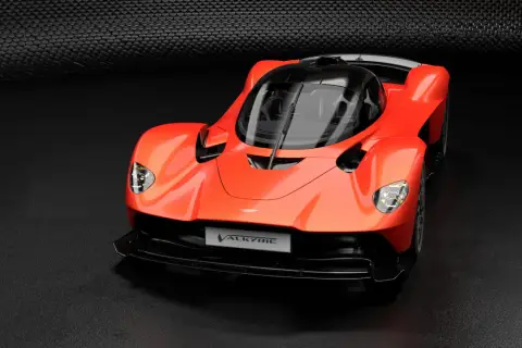 Pomarańczowy Aston Martin Valkyrie, supersamochód o futurystycznym designie, prezentuje swoje aerodynamiczne linie na ciemnym tle.