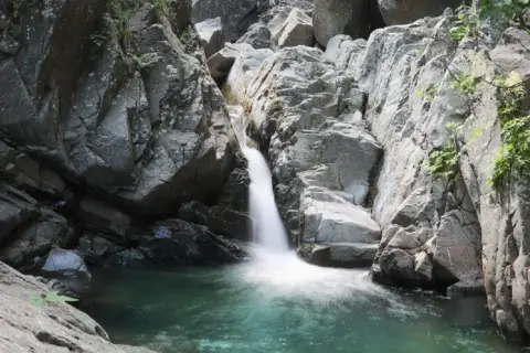 Cascate naturali in Lunigiana, con acqua cristallina che scende tra rocce grigie e vegetazione rigogliosa. Un angolo di paradiso selvaggio.