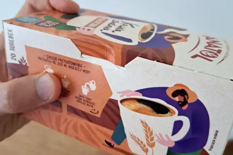 Opakowanie kawy zbożowej Anatol. Na boku instrukcja przygotowania i ilustracja rolnika z kubkiem kawy i kłosami zbóż.