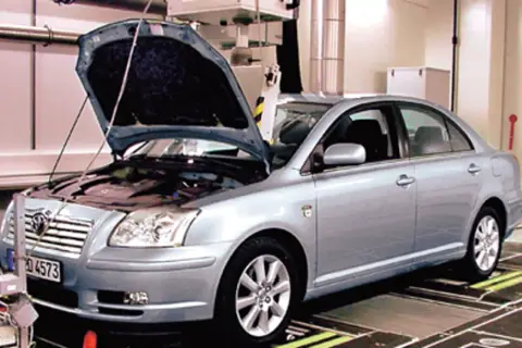 Srebrna Toyota Avensis 2.0 D4D z otwartą maską stoi na stanowisku diagnostycznym.
