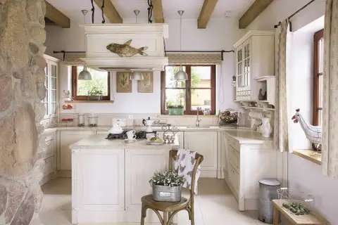 Jasna kuchnia w stylu cottage z kamiennym murem, drewnianymi belkami i rustykalnymi dodatkami.