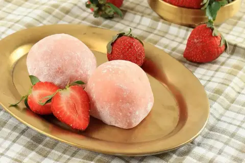 Różowe mochi z truskawkami na złotym talerzu. Idealne do wypróbowania, gdy szukasz przepisu na mochi.