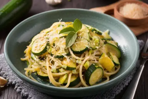 Proste przepisy na cukinię: spaghetti z cukinią, czosnkiem i parmezanem, udekorowane listkami mięty.