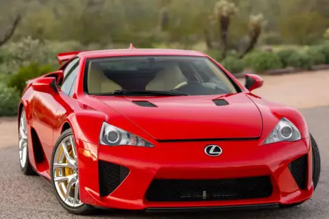 Czerwony Lexus LFA z żółtymi zaciskami hamulcowymi, zaparkowany na tle pustynnego krajobrazu.