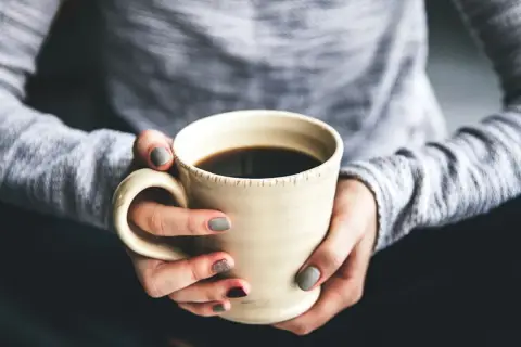 Dłonie trzymają kubek z kawą. Chcesz wiedzieć, jak zrobić kawę rozpuszczalną Nescafé? To proste!