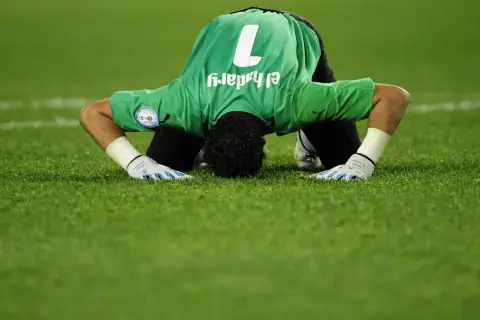 Bramkarz w zielonej koszulce z numerem 1, Essam El-Hadary, najstarszy piłkarz na mundialu, klęczy na murawie.