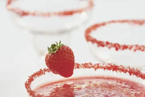 Truskawkowa margarita z ozdobnym brzegiem i świeżą truskawką.