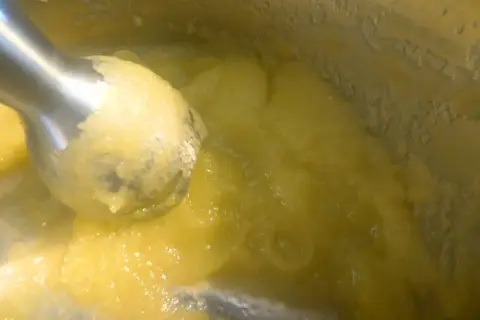 Blendowanie parowanej cukinii na puree dla niemowlaka. Zdrowy, żółty posiłek gotowy do podania.