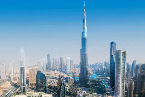 Widok z lotu ptaka na Dubaj, z dominującym Burdż Chalifa. Nowoczesne drapacze chmur i błękitne wody tworzą futurystyczny krajobraz.