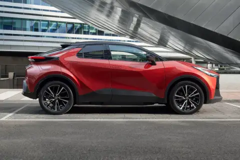 Nowoczesna, czerwona Toyota plug-in na tle futurystycznego budynku. Stylowy design i ekologiczna jazda.
