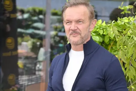 Cezary Pazura, znany aktor, w granatowym swetrze. Ile ma lat Cezary Pazura? Wiek aktora to tajemnica, ale wygląda świetnie!