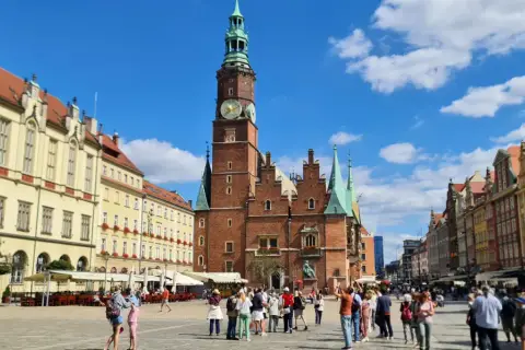 Tętniący życiem Rynek we Wrocławiu, z Ratuszem w centrum. Ludzie spacerują, podziwiając piękną starówkę wrocław.