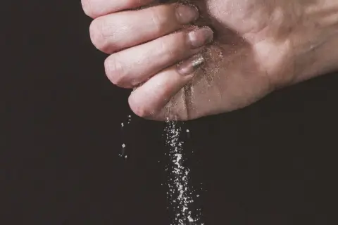Une main saupoudre du sel, une expression culinaire qui sublime les saveurs.