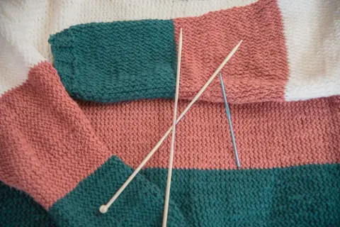 Kolorowy, dziergany sweter z drutami i szydełkiem.