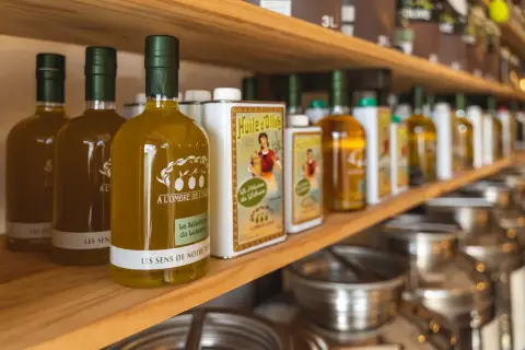 Bouteilles d'huile d'olive "Les Sens de Notre Terre", "A l'ombre de l'Oli" et "La Sélection du Luberon", évoquant les saveurs des terrasses d'Adrien.