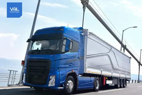 Niebieska ciężarówka z naczepą na moście, symbolizująca sprawną spedycję transport krajowy.