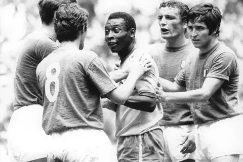 Słynny piłkarz brazylijski, Pelé, otoczony przez innych graczy, w geście sportowego szacunku po meczu.