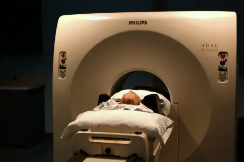 Pacjent leży na łóżku aparatu do tomografii głowy Philips ADAC Allegro.