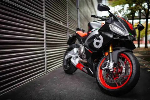 Aprilia RS 660, una moto deportiva negra con detalles rojos y naranjas, lista para la acción.
