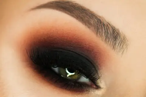 Oko z perfekcyjnym makijażem w stylu smokey eyes, podkreślone czernią i brązem.