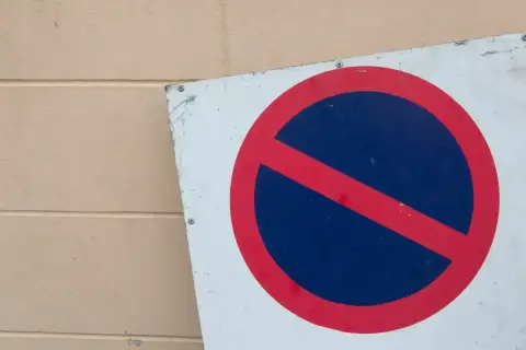 Znak b35 zakazu zatrzymywania się. Czerwone koło z czerwoną przekątną na niebieskim tle.