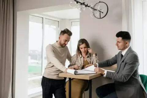 Para omówia plany z agentem nieruchomości, który pokazuje im dokumenty. Zastanawiają się, ile zarabia agent nieruchomości.