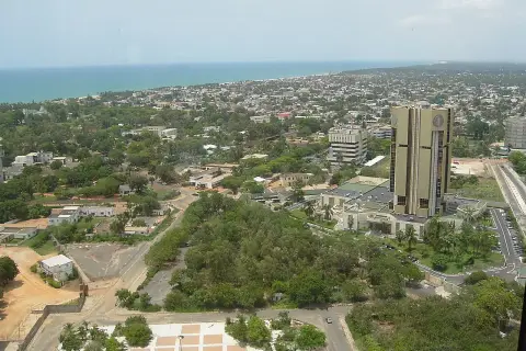 Widok na Lome, stolicę Togo, z dominującym złotym budynkiem i rozległym miastem w tle, nad którym rozciąga się ocean.