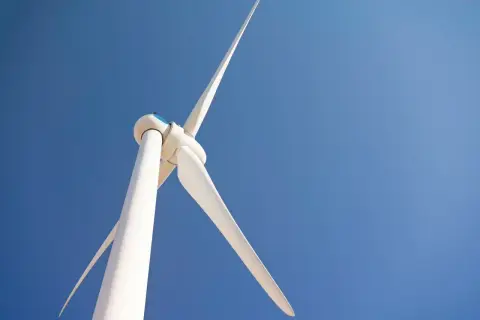 Biała turbina wiatrowa bez pozwolenia na tle błękitnego nieba.