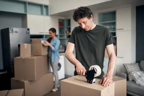 Mann packt Kartons für den Umzug. Bald wird er die umzugskosten steuerlich absetzen können.