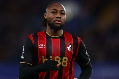 Piłkarz w koszulce Bournemouth z numerem 38, z uwagą śledzi rozwój wydarzeń na boisku, jakby czekał na swoje okno transferowe.