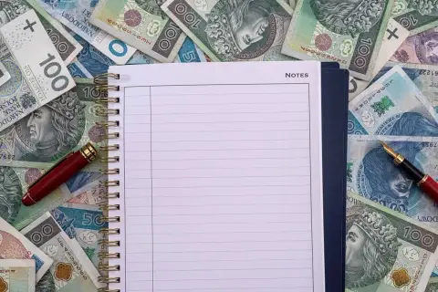 Notatnik i długopis na stosie polskich banknotów. Czy to miejsce na zapisanie, ile zarabia przewodniczący rady miasta?