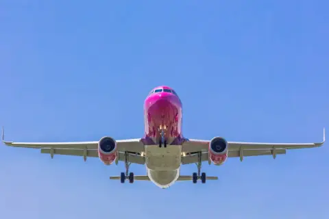 Różowy samolot Wizzair z wysuniętym podwoziem, gotowy do lądowania. Tak wygląda odprawa online Wizzair - szybko i sprawnie!